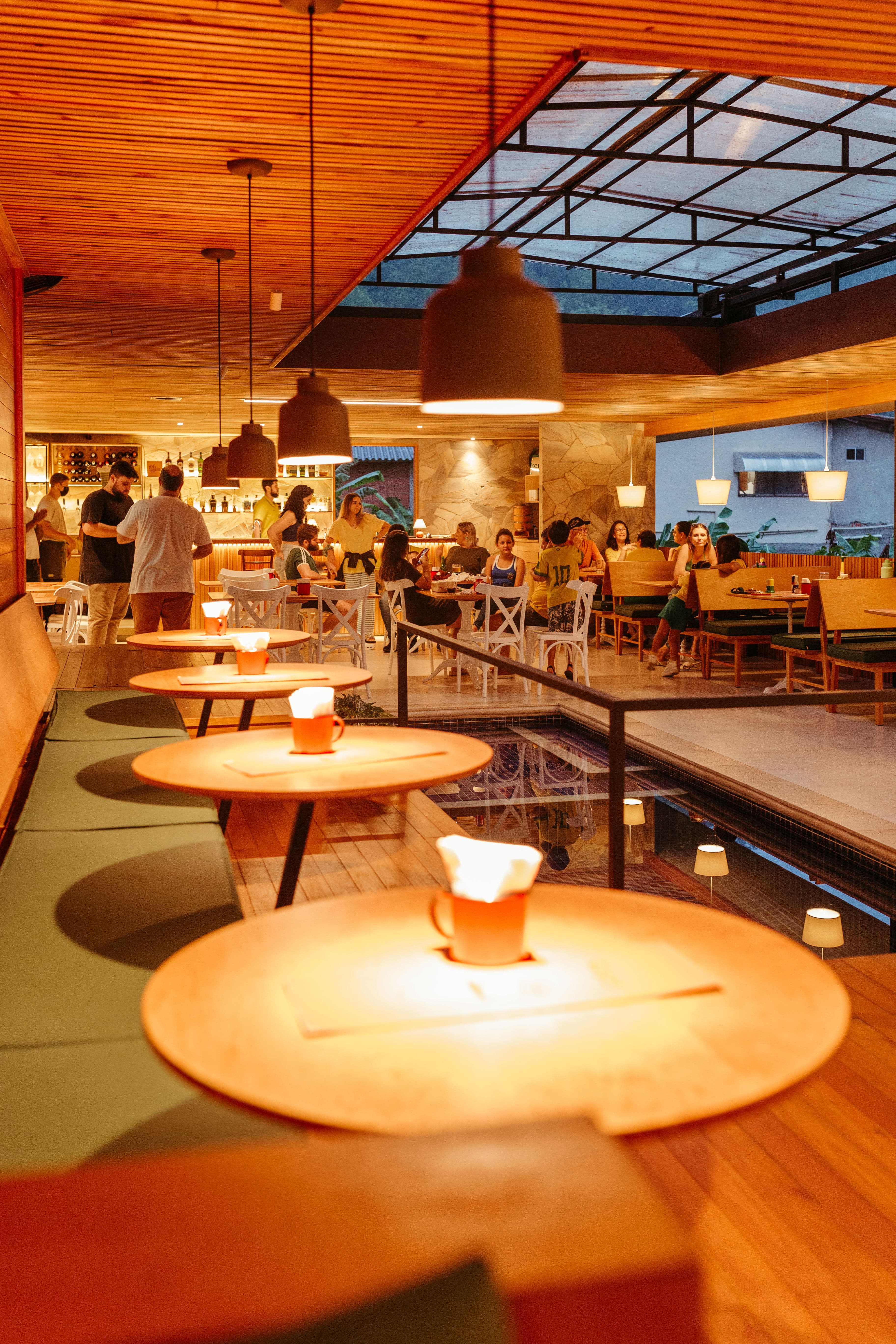 Warmly lit restaurant with round tables and diners in the evening